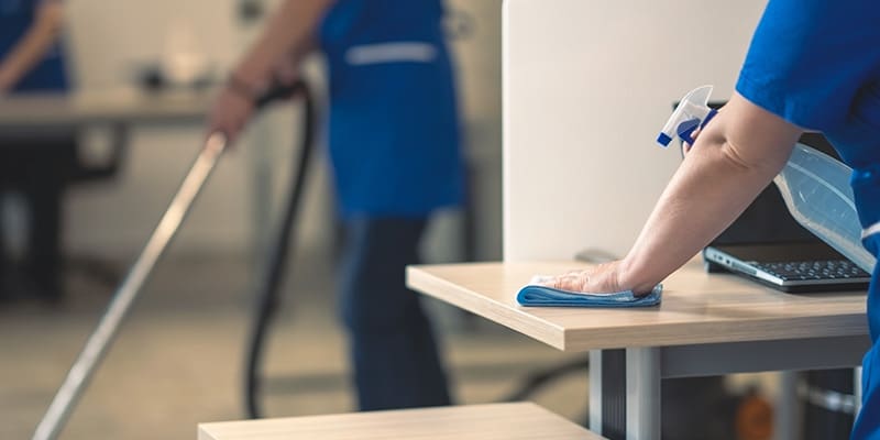 Industrial Cleaning Woman cleaning a table with a computer sitting on it